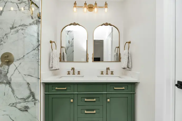 a bathroom with marble counter tops and green cabinets